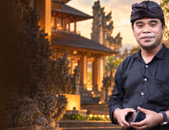Foto Agung Gempa dengan latar arsitektur Bali bergradasi cokelat, tanpa tulisan